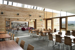 cafe space with horizontal timber cladding and tables and chairs inside a visitor centre