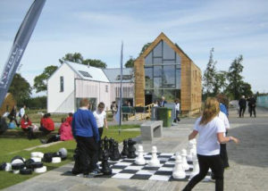 people playing a large chess game in the street outside the flower house