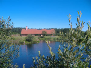 looking over a small loch to a red roofed single storey building