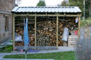 logs for burning in a log shed with a corrugated roof