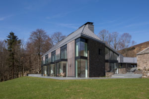 two storey house with timber cladding and large glass windows