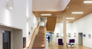 inside the main area of a centre with a timber staircase directly in front and timber clad underfloor ceiling