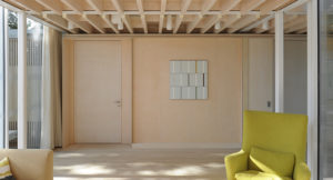 interior of a room with open timber ceiling panels and calming wall art and furniture