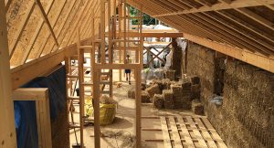 timber frame building with strawbales neing used to construct the interior walls