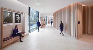 children walking along a corridor with a large vertical timber clad wall on the right