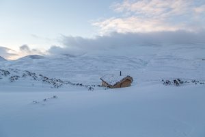 snow covered landscape with a timber bothy on it