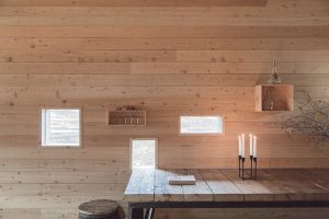 timber wall with an array of unusual windows and a rustic wooden bench with candels