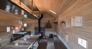 inside of timber bothy with large rustic bench and lots of unusual small windows