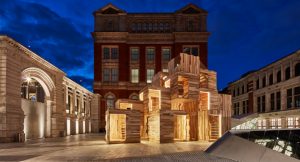 timber cube structure in a classic architectural courtyars illuminated at night