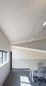 interior space with white timber walls, narrow horizontal windows and an office table and chairs