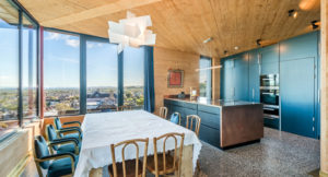 dining kitchern with clt walls and ceiling and blue kitchen units dining table and chairs in the corner where a large corner winder looks over the city of Edinburgh