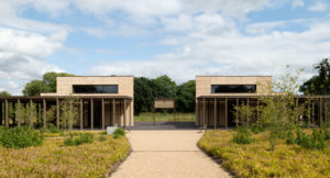 symetrical split building with narrow pillars to the front and path leading towards the entrances with grass on either side