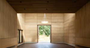 interior of cemetry with rammed earth walls looking outside to a tree